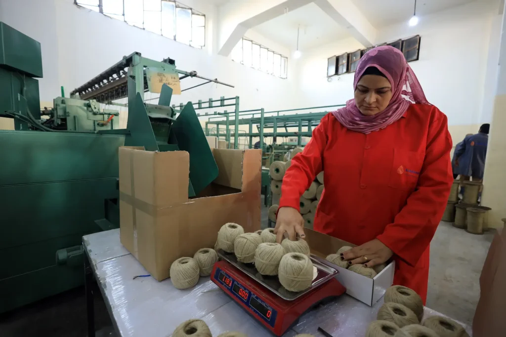Worker weighing linen yarn balls at El Nawawy Company factory for customized weight and size packaging